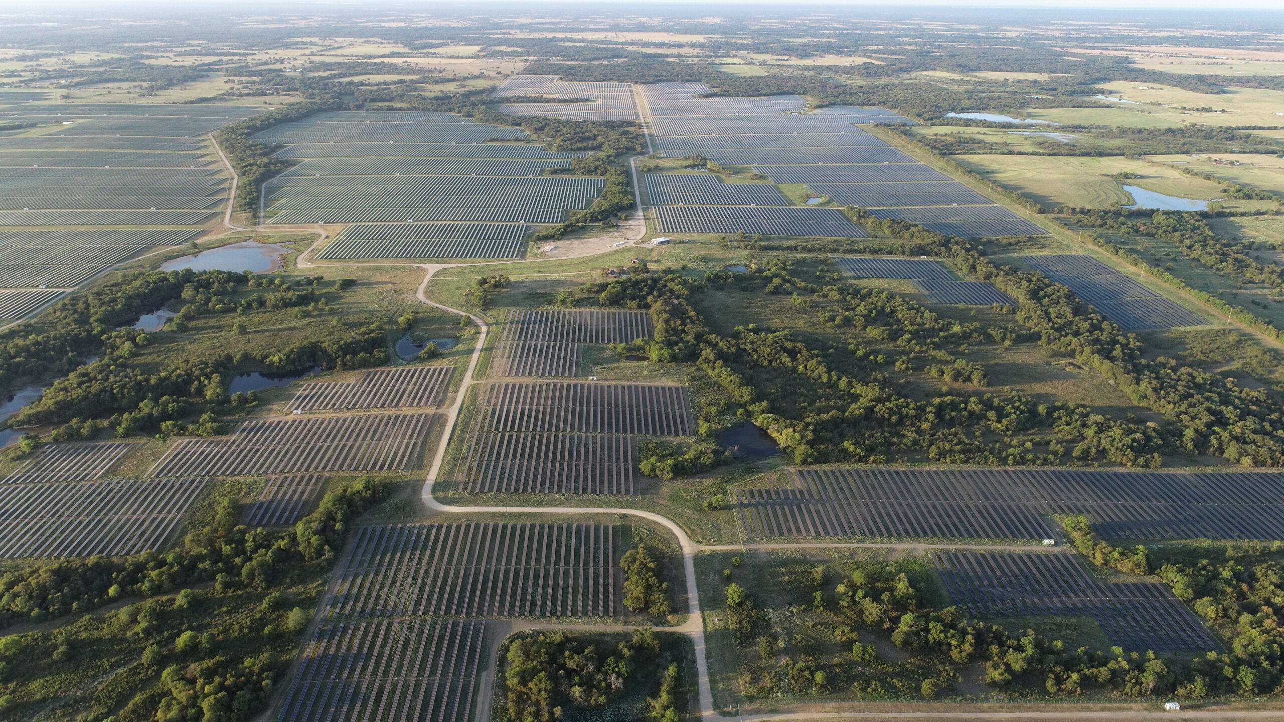 A wide landscape dotted with many large industrial solar arrays