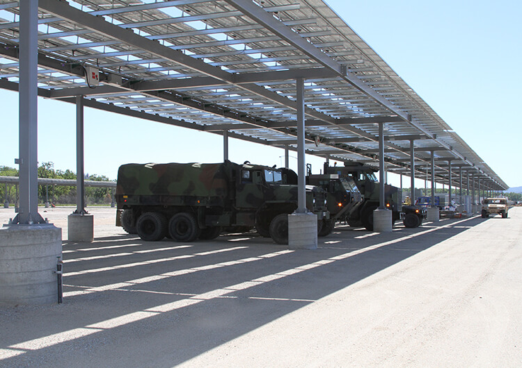 Camo army trucks parked underneath a large solar array