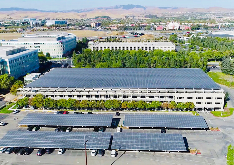 Solar panels covering a parking lot and large office building behind it