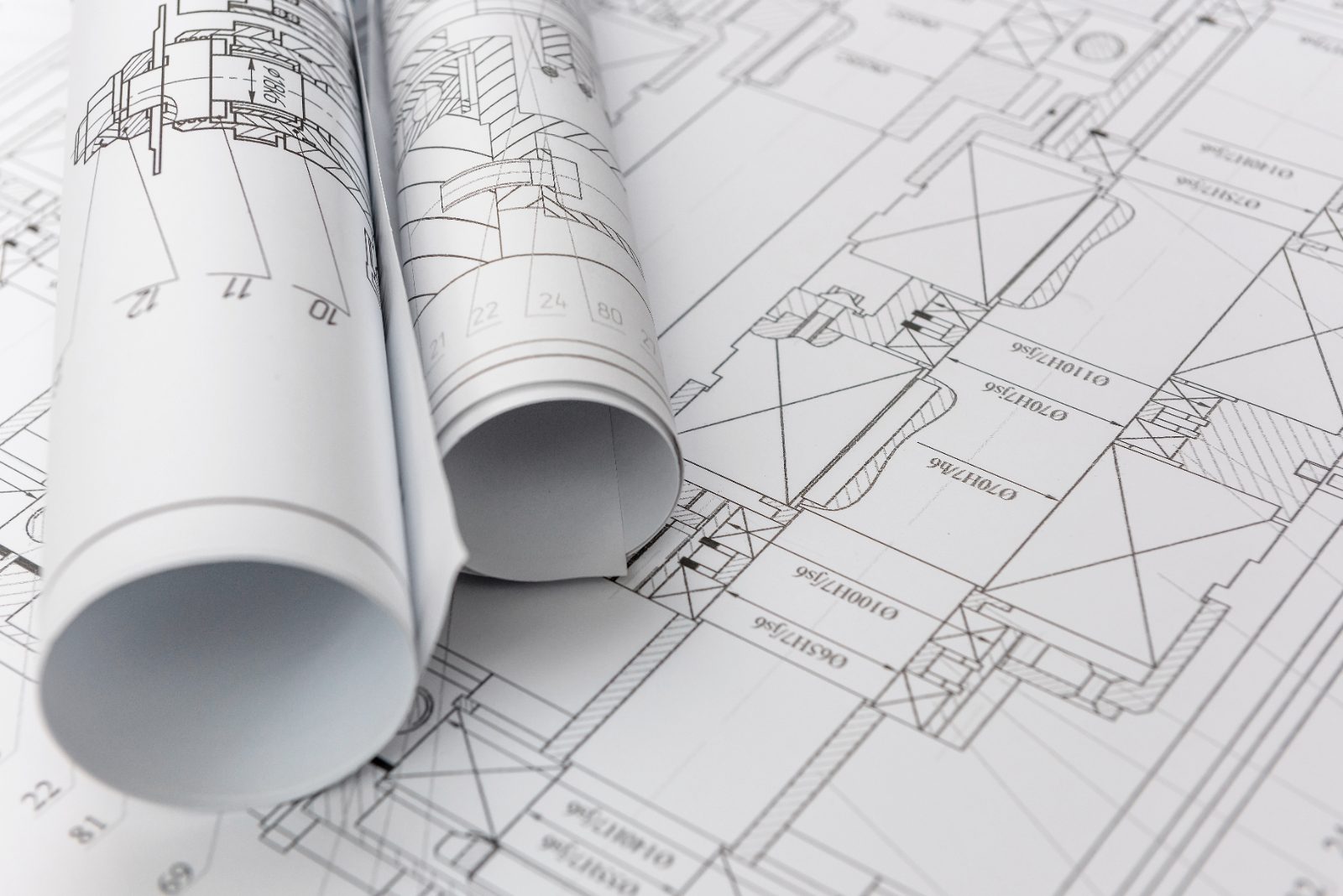 Rolled engineering drawings resting on a set of technical building plans